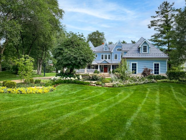 A blue house with a green lawn represents spring landscaping ideas for a garden in DuPage County, IL